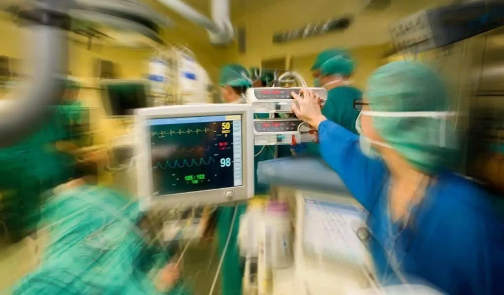 Medical personnel operating monitoring equipment in a surgical environment.