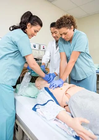 Two medical professionals performing CPR on a manikin in a training environment.
